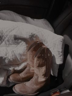 a pair of cowboy boots sitting on top of a car seat next to a blanket