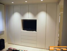 an entertainment center with white cabinets and a flat screen tv mounted to the side of it