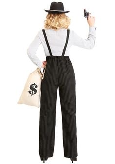 a woman wearing overalls and a hat holding a bag with dollar signs on it