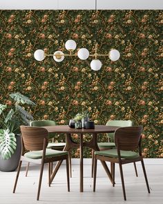 a dining room table with green chairs next to a wall covered in floral wallpaper