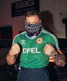 a man wearing a green shirt with a checkered mask on his face and arms