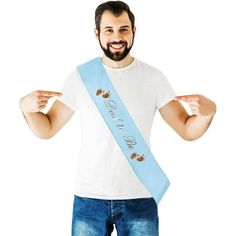 a man wearing a white shirt and blue sash holding his hands up in the air