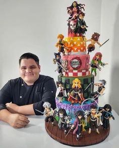 a man sitting in front of a cake with many figurines on top of it