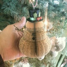 a hand holding an ornament in front of a christmas tree