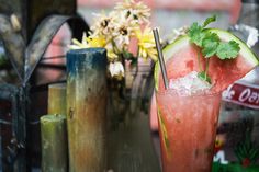 a watermelon and cucumber drink sitting on a table next to flowers