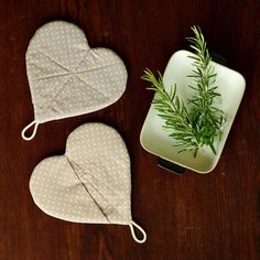 two heart shaped pot holders on top of a wooden table next to a small plant