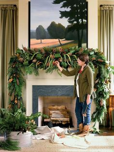 a woman standing in front of a fireplace decorated with christmas greenery and pine cones