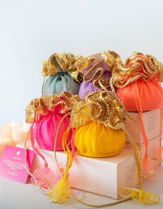 several small bags with gold trimmings on top of each other and some candles in the background