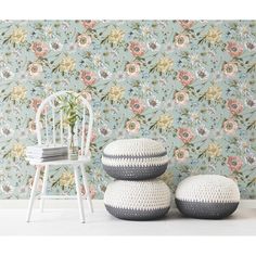 two white stools sitting in front of a wallpapered with flowers and leaves