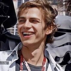 a young man is smiling in front of some star wars characters, including darth vader and stormtrooper