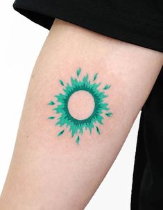 a green circle tattoo on the left arm