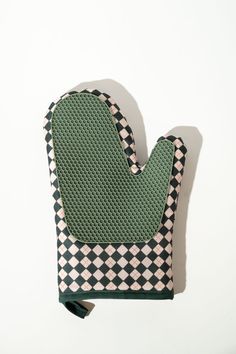 a green oven mitt sitting on top of a white counter next to a black and white checkered pot holder