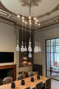 a dining room table with chairs and chandelier hanging from it's ceiling