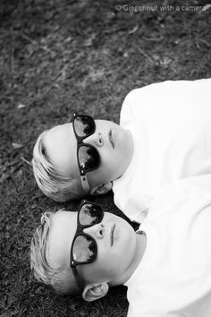 two young boys laying on the ground wearing sunglasses