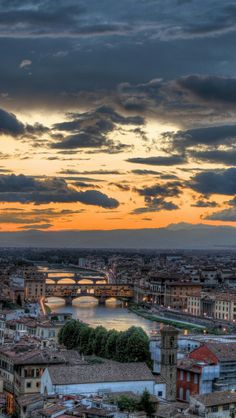 the sun is setting over an old city with bridges and buildings on it's sides