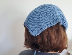 a woman wearing a blue crocheted hat on top of her head and shoulder