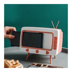 a small tv sitting on top of a table next to crackers and a plate