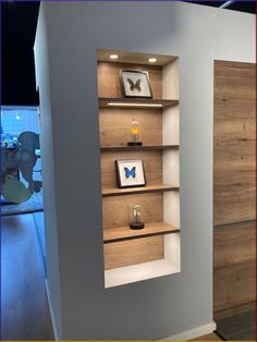 an empty shelf in the corner of a room with some pictures on it and a butterfly