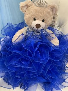 a teddy bear wearing a blue dress with a tiara