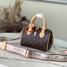 Inspired by classic travel bags, the Speedy Bandoulière 20 features Monogram canvas and calfskin trim with rolled leather handle and padlock. The brand logo is embellished with a detachable shoulder strap, which can be switched over the shoulder and crossbody at will. 

Dimensions: 20.5 x 13.5 x 12 cm Crossbody Bags With Branded Hardware In Monogram Canvas, Satchel Bags With Branded Hardware And Monogram Canvas, Luxury Bag In Signature Coated Canvas, Luxury Bag With Signature Coated Canvas And Handles, Luxury Signature Coated Canvas Bag With Handles, Luxury Signature Coated Canvas Bag, High-end Bags With Branded Hardware And Coated Canvas, Luxury Monogram Canvas Crossbody Satchel, Luxury Crossbody Bag In Signature Coated Canvas