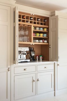 a kitchen cabinet with wine glasses and cups in it