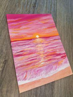 a piece of paper that has been painted with watercolors and is sitting on a table