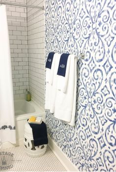 a bathroom with blue and white wallpaper and towels hanging on the shower curtain rod