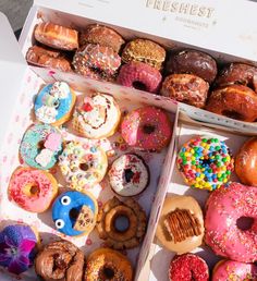 a box filled with lots of different flavored donuts on top of a table