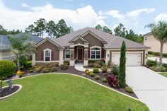 a house with landscaping in front of it and trees around the driveway area on either side