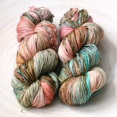 three skeins of yarn sitting on top of a white bowl filled with multicolored yarn