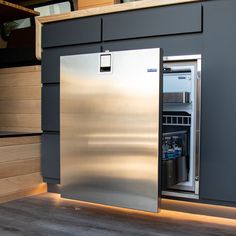 a stainless steel refrigerator with its door open in front of a wooden wall and stairs