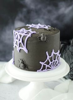 a halloween cake decorated with purple icing and spider webs