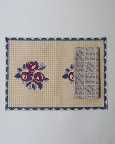 a piece of cloth with flowers on it next to a pair of blue and white napkins