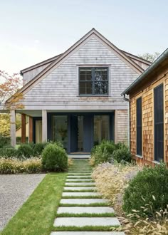 a house with stone steps leading to the front door and side entrance, surrounded by greenery