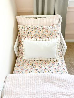 a white crib with flowers and pom - poms on the bedding