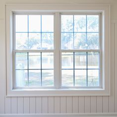 an empty room with two windows and white paneling