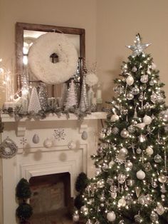 a decorated christmas tree sitting in front of a fire place next to a white fireplace