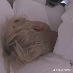 a blonde haired woman laying in bed with her head on the pillow