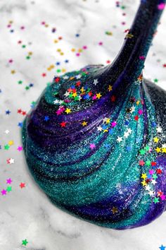 a purple and blue vase sitting on top of a white table covered in colorful stars