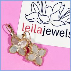 Designer-inspired gold-tone flower-shaped earrings in a drop style, with iridescent mother-of-pearl petal insets and accented by tiny CZ stones for extra sparkle in the center. They have a surgical steel post secured with a lever back. The pendant is 1/2" square, and they hang 1 1/4" long. Imported for the Leila Jewels Glam Collection Luxury Flower-shaped Mother Of Pearl Earrings, Steel Post, Cz Stone, Mother Of Pearl, Gold Tones, Design Inspiration, Sparkle, Drop Earrings, Square