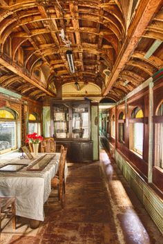 the inside of a train car with tables, chairs and windows on each side of it