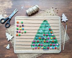 a christmas tree made out of beads and pins on a piece of fabric with scissors