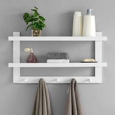 two white shelves with towels and soaps on them next to a potted plant