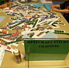 several people sitting at a table covered in paper and crafting supplies, with one person holding a pencil