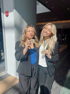 two women standing next to each other holding medals