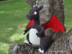 a crocheted dragon sitting on top of a tree