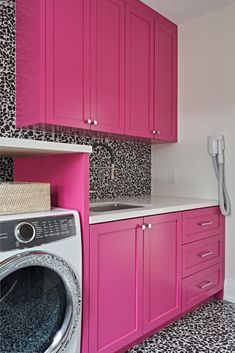 a laundry room with pink cabinets and leopard print wallpaper on the walls, along with a washer and dryer