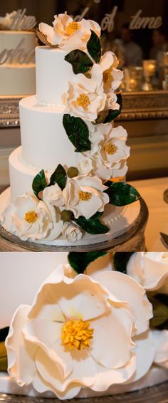 a three tiered cake with white flowers on top and green leaves in the middle