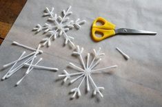 the snowflakes are made out of white sticks and yellow handled scissor