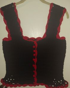 a crocheted top hanging on a wall with a buttoned up front and back